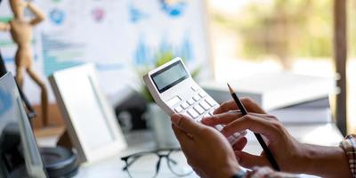 Mujer de negocios con calculadora y computadora portátil en el escritorio de oficina blanco, concepto de contabilidad con espacio de copia foto