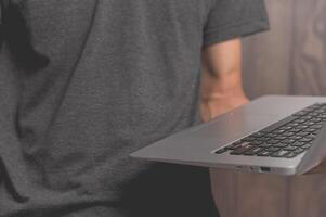 A standing man using a laptop computer photo