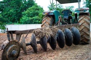 Cerca de gradas de discos en la parte trasera de un tractor. Cuchillas de acero sucias de un tractor con tierra y paja seca foto