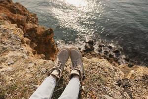 Woman's feet lying next to a cliff near the sea photo