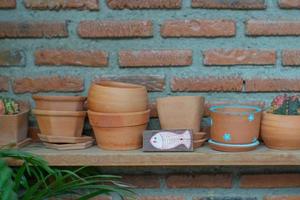 Close up of empty clay pots on the wooden shelf with blurred bricklayer wall background photo