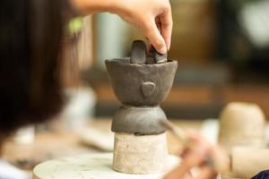 Close up of clay work with hands of a girl decorating her work by putting mud with a blurred foreground and background photo