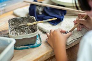 Motion blurred hands of a girl molding clay work with wet mud in a plastic tray photo