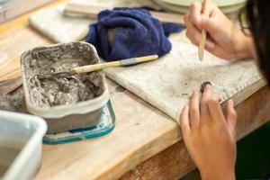 Motion blurred hands of a girl molding clay work with wet mud in a plastic tray photo