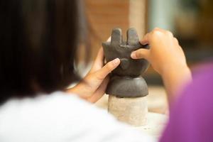 Close up of clay work with hands of a girl decorating her work by putting mud with a blurred foreground and background photo