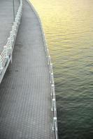 Empty concrete walkway along the bank of a river with light reflection from the sun photo