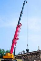 High-angle view of a group of workers pouring mixed cement from a big steel bucket hanging from a crane. photo