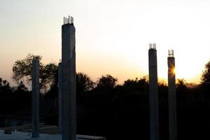 Primer plano de columnas de hormigón que reflejan la luz del sol en un sitio de construcción con un fondo de cielo azul foto