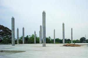 Perspectiva de columnas de hormigón de pie sobre el piso de cemento en el sitio de construcción con fondo de cielo despejado foto