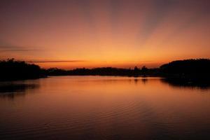 paisaje de puesta de sol y cielo crepuscular con el lago en primer plano foto