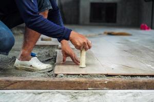 Selective focus on hand of worker installing the floor tile with motion blurred hand at the construction site photo