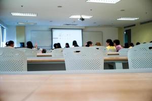 El enfoque selectivo en la fila de sillas vacías con un grupo de estudiantes borrosa en segundo plano. foto