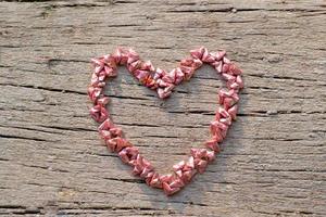 Top view of folding paper in little heart shape put on the wooden surface photo