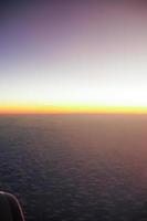 Light of sunset on the horizon with blue sky background and shadow from an aircraft window in the foreground photo