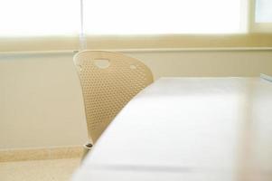 Selective focus on steel chair and table in classroom with sunshine behind defocused curtain background photo