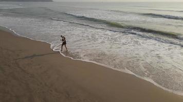 tocando o conceito de natureza, mulher asiática relaxando com a praia, oceano de mar tropical com viajante em conceito de conexão natural, relação humano e natureza, tempo de férias de liberdade, vista aérea lenta video