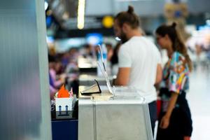 enfoque selectivo en el mostrador de metal de la aerolínea en el aeropuerto con antecedentes de facturación de pasajeros desenfocado. foto