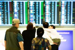 Grupo borroso de personas de pie delante y mirando el monitor de horario de vuelo foto