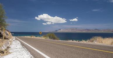 Road from Loreto to Santa Rosalia in the state of Baja California Sur Mexico near Punta Armenta in the region of Bahia Concepcion with the sea of Cortes and blue sky with cloud and mountains photo