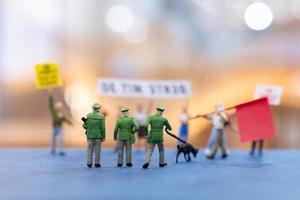 Miniature people, protesters holding signs, raising their hands for revolution photo