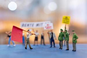 Miniature people, protesters holding signs, raising their hands for revolution photo