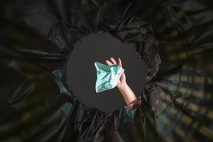 Throwing a face mask into the trash. With a worm view from the inside of the trash bin. photo