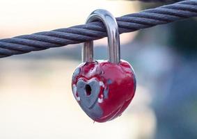 Red peeling wedding lock on a rope with a key hole photo