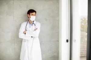 médico con una máscara mientras mira por una ventana foto