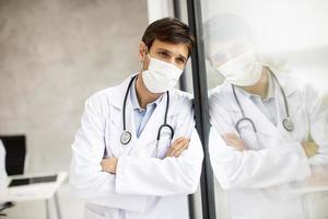 Doctor apoyado contra una ventana mientras usa una máscara foto