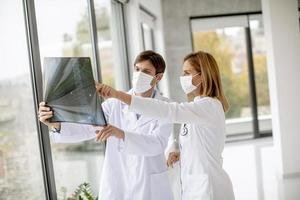médicos con máscaras faciales protectoras examinando una radiografía foto
