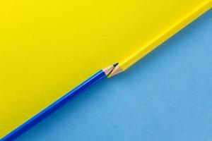 Color pencils on yellow and blue color papers arranged diagonally