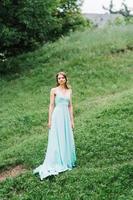 Happy girl in a turquoise long dress in a green park photo