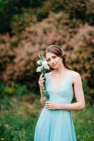 Happy girl in a turquoise long dress in a green park photo