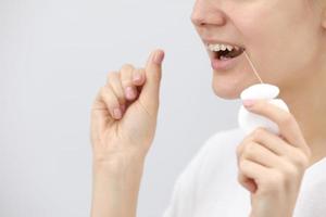 Smiling women use dental floss on a white background photo