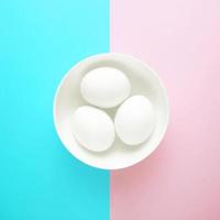 tres huevos sobre un fondo rosa y azul foto