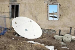 un satélite blanco y una casa abandonada. foto