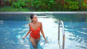 Joven mujer asiática relajándose alrededor de una piscina al aire libre video