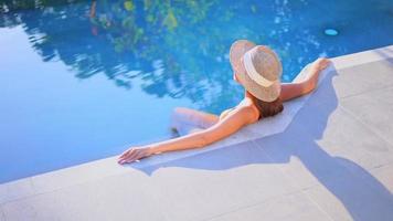 jovem mulher asiática relaxando ao redor de uma piscina ao ar livre