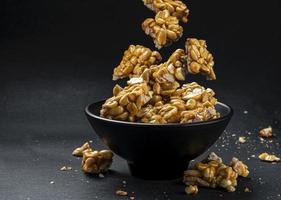 Peanut kozinaki falling in bowl on black background photo