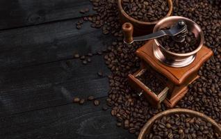 Ground coffee coffee mill bowl of roasted coffee beans on black wooden background top view photo