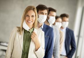 Woman taking off her mask with team behind her photo