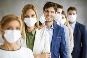 Row of professionals wearing masks with man taking off mask photo