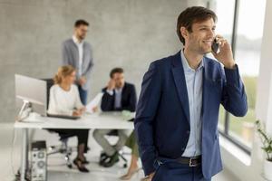 Man talking on phone with team in background photo