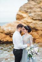 Bride in a blue dress with groom walking along the ocean shore photo