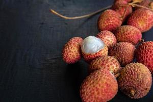 Fresh lychee fruit on a black wooden background. photo