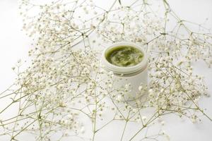 Opened plastic container with cream and flowers on a white background photo