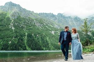 Young couple on a walk near the lake surrounded by the mountains photo