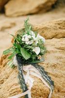 Bouquet of a bride from roses lies on a sandstone