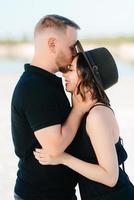 Young couple a guy and a girl with joyful emotions in black clothes walk through the white desert photo