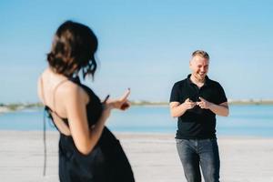 Young couple a guy with a girl in black clothes are walking on the white sand photo